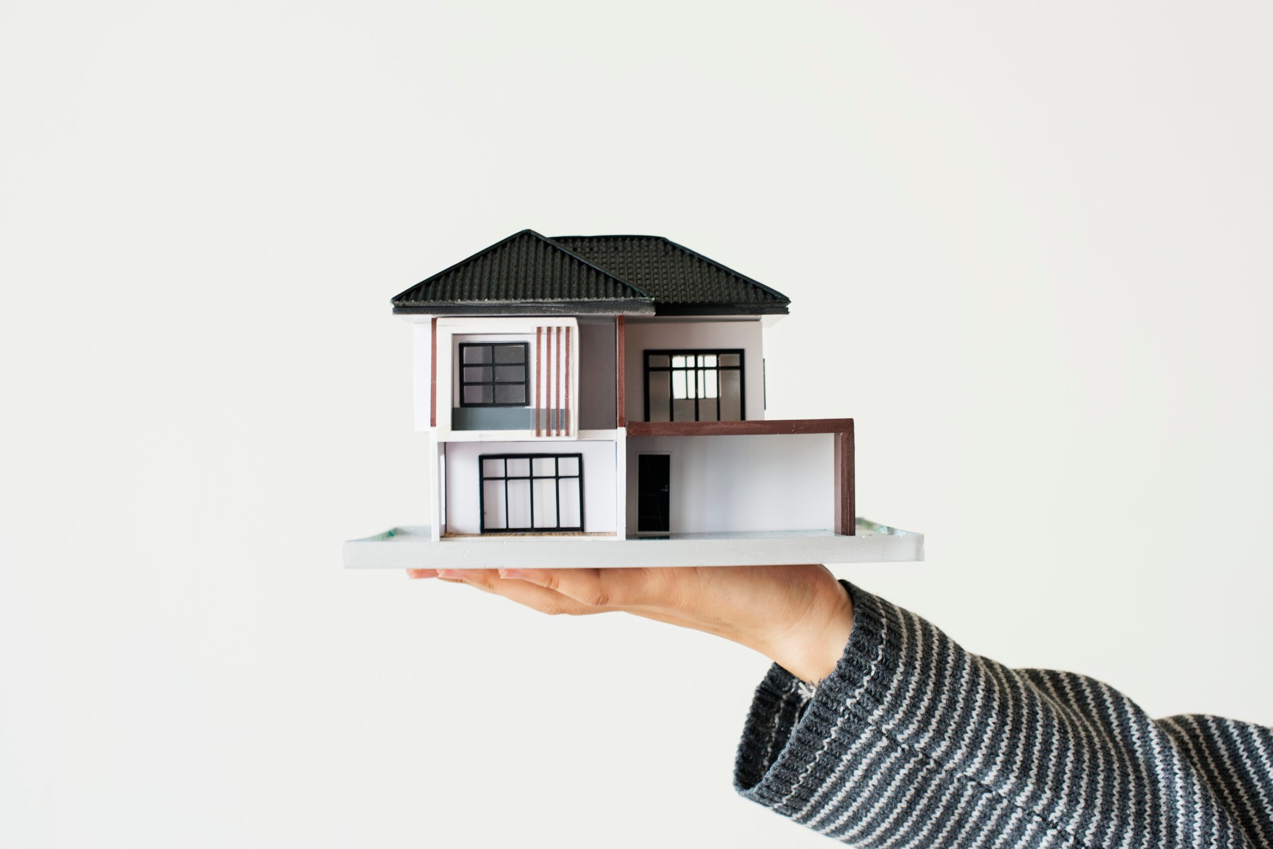 Hand holding a model house representing a Sydney home purchase